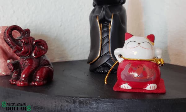 Japanese beckoning cat figurine beside other statues