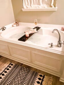 Wood tray with items on it over bathtub of bubbles