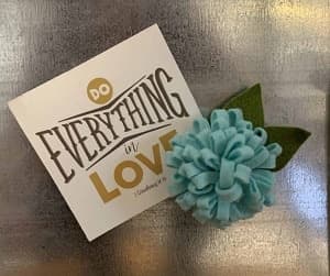 Blue felt flower magnet with "Do everything in love" sign